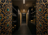 Alhambra geometric wallpaper installed as living room feature wall — Moroccan star pattern in warm neutral tones with brass and linen furnishings