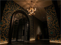 Alhambra geometric wallpaper installed as living room feature wall — Moroccan star pattern in warm neutral tones with brass and linen furnishings